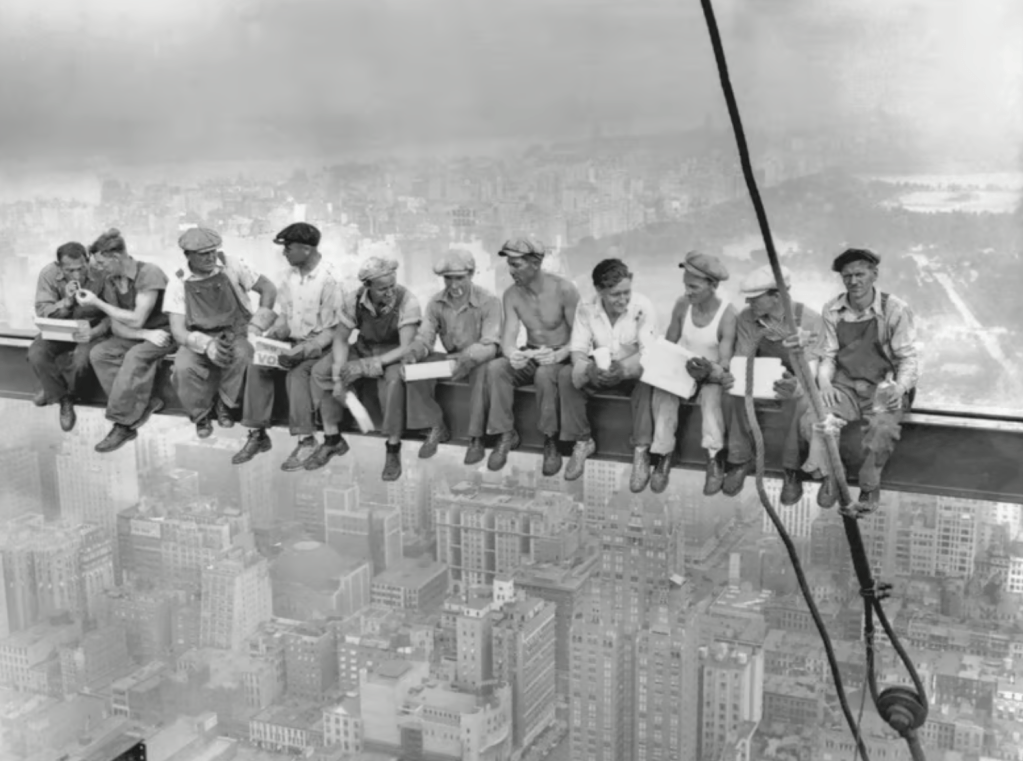An iconic black and white photo of eleven construction workers sitting on a steel beam high above a city skyline, enjoying lunch and gazing at the view.