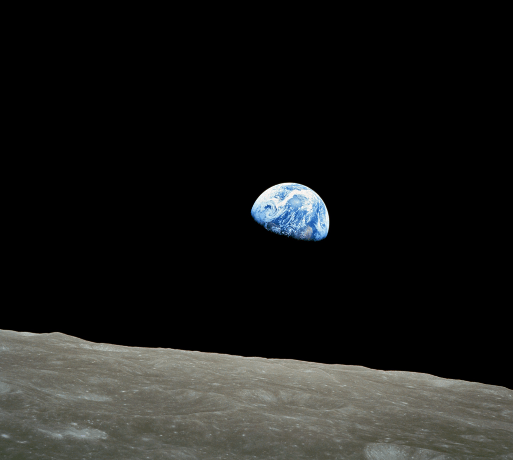 A view of Earth rising above the lunar surface, showcasing the blue planet partially illuminated against a black background.